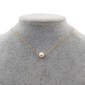Minimalist gold necklace with a single white pearl pendant on a velvet mannequin