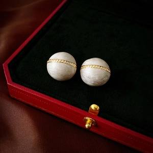 Detailed close-up of spherical vintage marble studs with gold chain in a classic velvet box