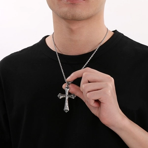 Close-up of a silver gothic cross pendant with a lion head and wings on a twisted chain