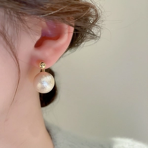 Vue macro d'une boucle d'oreille vintage dorée avec perle texturée blanc cassé