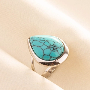Macro shot of an adjustable silver ring featuring a teardrop-shaped turquoise stone