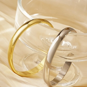 Minimalist C-shaped titanium steel cuff bracelets in gold and silver finish on glass