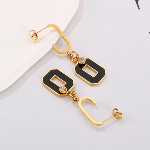 Detailed close-up of geometric gold-tone earrings with black enamel and clear rhinestone