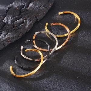 Close-up of minimalist C-shaped open bangles in gold, rose gold, silver and black finishes