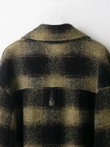 Close-up of green and black plaid wool blend fabric texture on the coat collar