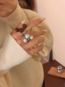 Detailed close-up of layered open ring with brown and marble beads on a female hand