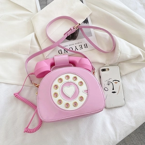 Close-up of retro pink telephone-shaped crossbody bag with dial and handset details