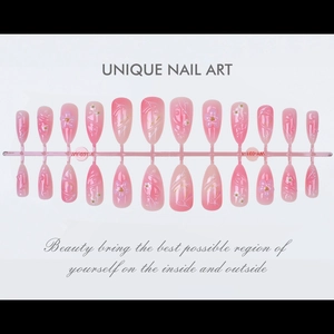 Detail of pink gradient press-on nails with 3D embossed flowers and pearl accents