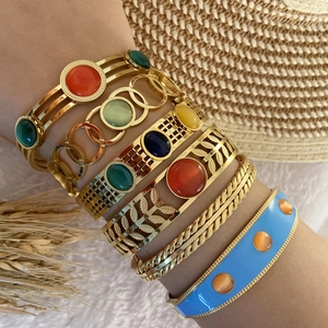 Detail of bohemian gold bracelets with multi-color gemstones and blue enamel finish