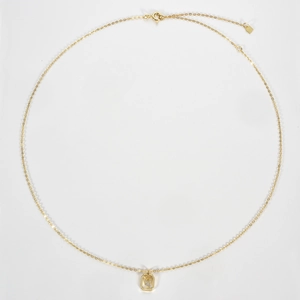 Close-up of golden S925 silver necklace with V letter octagonal pendant and crystals