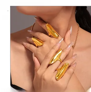 Detailed view of four irregular polished gold rings and bead chain on model fingers