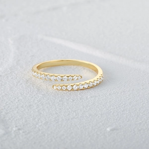 Close-up of golden crossover open ring featuring sparkling pave cubic zirconia stones