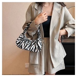 Close-up of zebra pattern pleated underarm bag worn with a stylish beige outfit