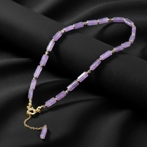 Elegant purple amethyst beaded necklace with gold accents on black textured background
