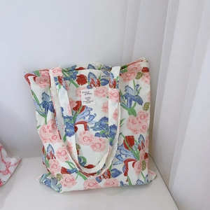 Detailed view of floral canvas tote bag showing pink rose prints and sewn brand label