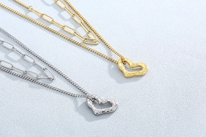 Detail of gold and silver layered necklaces with textured irregular heart pendants