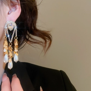 Detail of luxury teardrop pearl tassel earrings with gold plating and sparkling crystals