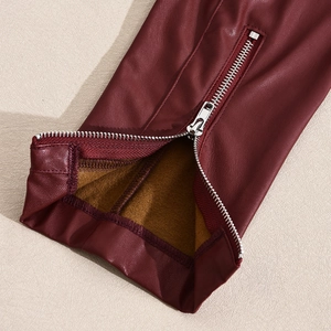 Detail of burgundy PU leather jacket featuring silver metal zipper and brown fleece lining