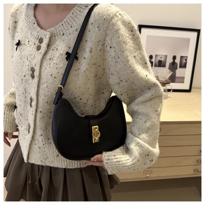 Detail of a black crescent underarm bag with a golden metal buckle and adjustable strap