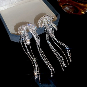 Macro detail of silver bow tassel earrings with sparkling rhinestones on jewelry box