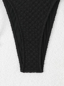 Close-up of black bikini bottom with premium bubble textured fabric and refined stitching