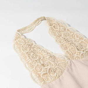 Détail de l'encolure en dentelle beige et motif à carreaux sur une robe licou