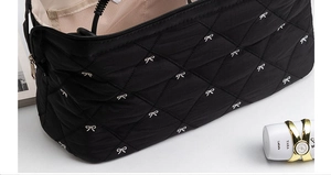 Detail of black quilted storage bag with bow embroidery and pink mesh compartments