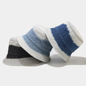Détail de bobs en jean délavé avec motifs tie-dye et coutures précises sur le bord