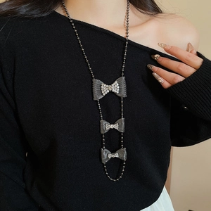 Detail of layered bow pendant necklace with crystals on model in dark silver