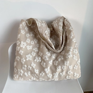 Detailed view of beige tote bag with textured floral embroidery on premium canvas fabric