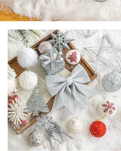 Detail of silver glitter bow with festive white and red ornaments on faux snow