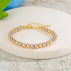 Detail view of tri-color metal beaded bracelet with adjustable chain on marble