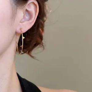 Irregular golden hoop earrings with studded spikes shown on model in a stylish close-up view