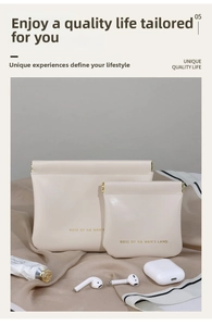 Close-up of cream leather pouch set with golden metal spring closure and luxury branding