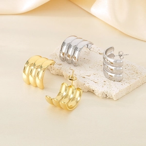 Detailed view of polished C-shaped triple layer hoop earrings in gold and silver finish