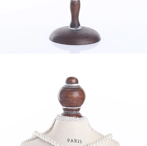 Detail of bust display stand with wooden base and beige fabric featuring Paris text