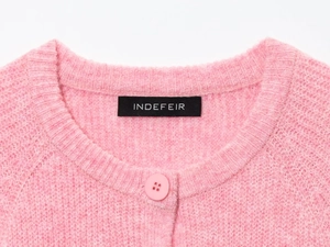 Close-up of pink knit cardigan showing soft wool texture, round neck, and matching buttons