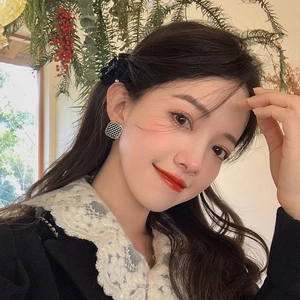 Model wearing square checkered earrings with gold frame in a warm interior setting