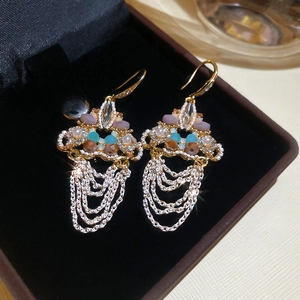 Macro shot of Bohemian gold tassel earrings with colorful beads on black velvet