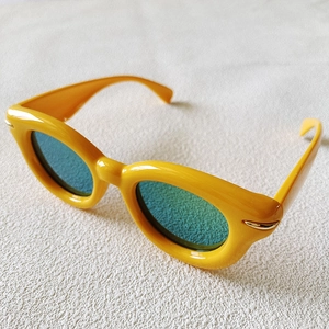 Detailed close-up of yellow thick frame sunglasses with blue lenses and gold metal accents