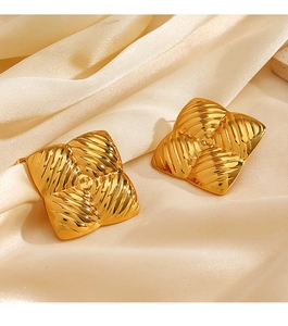 Macro detail of gold square earrings with vintage radial ridges on beige satin silk fabric