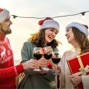 People cheering with PVC Christmas wine glass charms including Santa and reindeer icons