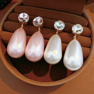 Détail de boucles d'oreilles perles en forme de larme roses et blanches dorées
