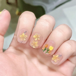Detailed view of handmade short press-on nails with 3D yellow tulip and green vine design