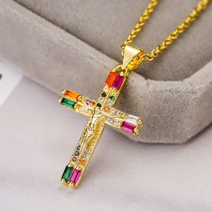 Golden crucifix necklace with colorful cubic zirconia crystals on a jewelry display box