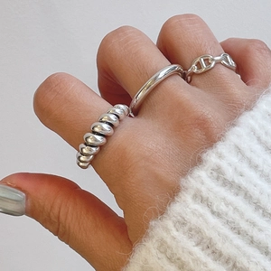 Close-up of stacked silver 925 knotted rings and pig nose link design on fingers