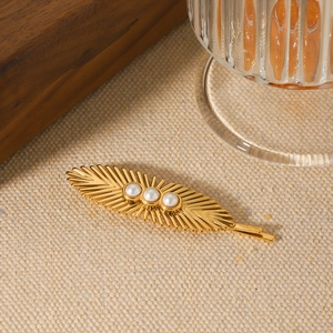 Golden sunburst stainless steel hair clip with three white pearls on canvas background