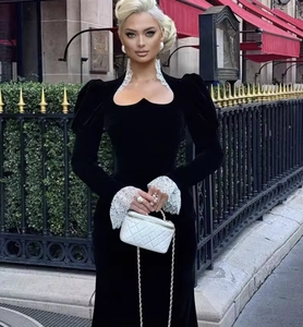 Dettaglio di un elegante abito in velluto nero con colletto in pizzo bianco e scollo a cuore