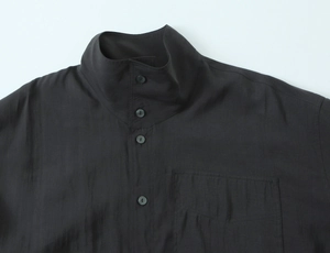Close-up of black poplin shirt featuring a stand collar and detailed chest pocket texture