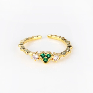 Macro view of adjustable gold ring featuring three green heart-shaped zircons and textured band